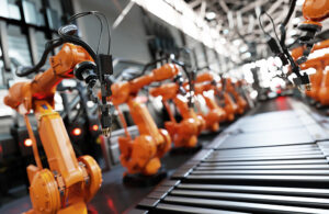 Orange robotic arms working on a manufacturing line.