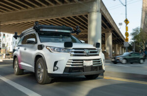 a sensor equipped zoox test vehicle passes under an over pass.